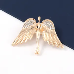 Primer plano detallado de un broche de ángel dorado con brillantes imitaciones.