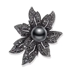 Detailansicht einer Vintage-Blumenbrosche mit schwarzer Perle und Strassbesatz