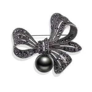 Detailansicht einer Vintage-Strass-Schleifenbrosche mit einer großen schwarzen Perle