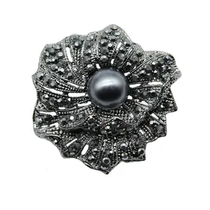 Detailansicht einer Vintage Blumenbrosche mit dunkelgrauer Perle und schwarzen Kristallen