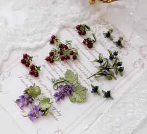 Detailed view of vintage fruit jewelry set including grape brooches and berry earrings