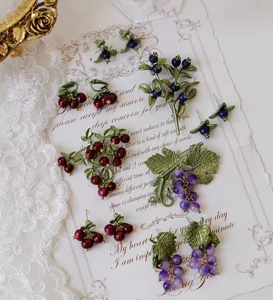 Vintage fruit jewelry set detail with grape, blueberry and berry brooches and earrings
