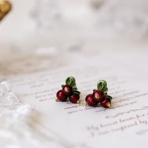 Close-up of vintage forest style red berry earrings on elegant paper background