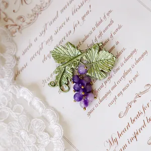 Exquisite close-up of a vintage purple grape brooch with detailed green enamel leaves