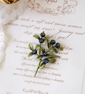 Detailed close-up view of a vintage blueberry berry brooch on a romantic cursive text card