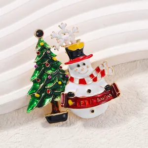 Broche de Noël festive avec bonhomme de neige et sapin, design banderole 'Let it Snow'.