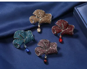 Elegant bow-shaped crystal brooches in four colors on blue silk background.