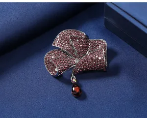 Detailed view of a purple rhinestone flower brooch with a red teardrop gem pendant