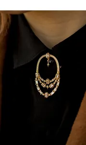 Gros plan d'une broche ajourée de style méditerranéen avec cristaux sur une chemise noire