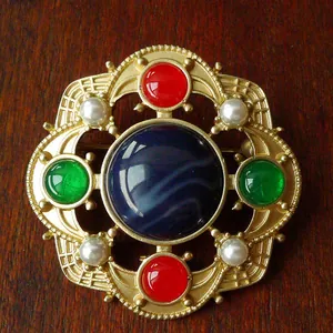 Macro view of vintage Baroque brooch with blue, red, green stones and faux pearls