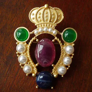 Detailed view of a vintage Baroque crown brooch with purple, green stones and pearls