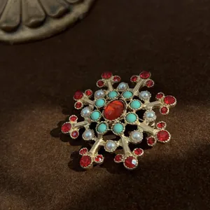 Dettaglio di una spilla a croce vintage barocca con pietre rosse e perle