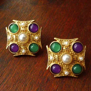 Close-up of vintage Baroque brooches with pearls and colorful gemstones on dark wood