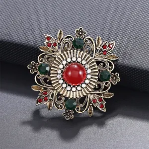 Vue détaillée d'une broche de style cour vintage avec pierres rouges et vertes.
