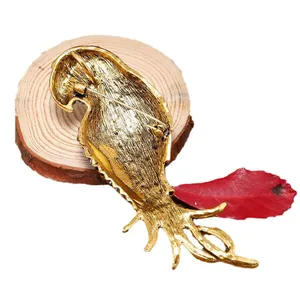 Vintage golden parrot brooch with detailed feather design on rustic wood background