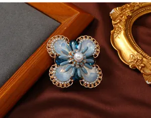 Detailed view of a vintage floral brooch featuring blue opal stones and a central pearl.