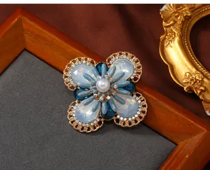 Close-up detail of a vintage floral brooch with blue opal stones and pearl center