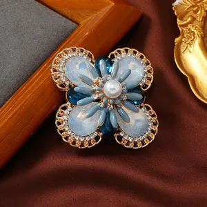 Vintage floral brooch with white opal-like stones, blue petals, and central pearl