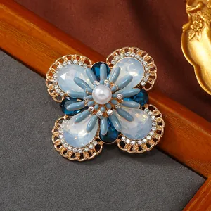 Elegant vintage floral brooch featuring blue and white stones and a central pearl