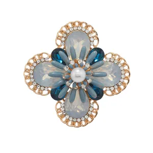 Vintage flower brooch with blue opal stones and pearl accent on white background