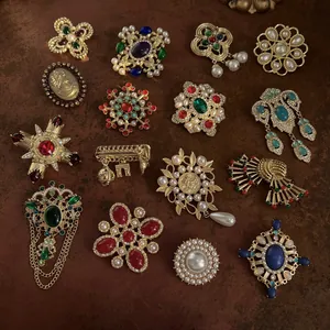 Collezione di spille barocche vintage in oro con perle e gemme colorate.