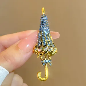 Detailansicht der Vintage-Regenschirm-Brosche mit blauen Strasssteinen und Gold