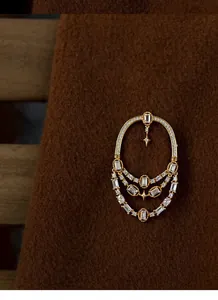 Gros plan d'une broche ajourée dorée de style méditerranéen avec des cristaux