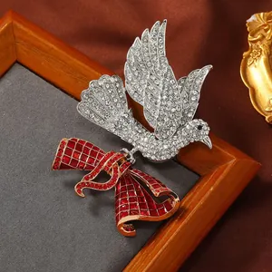 Dettaglio di una grande spilla vintage a uccello con strass e un fiocco rosso.