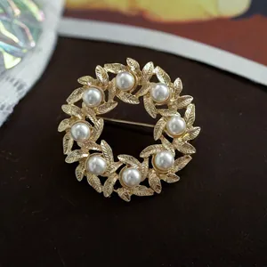 Elegant close-up view of a vintage golden wreath brooch decorated with white pearls