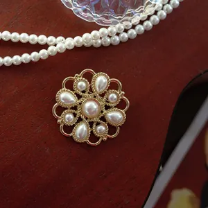 Detailed macro view of vintage Baroque brooch with elegant pearls on a dark wooden surface