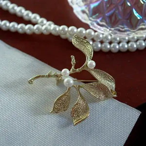 Detailed close-up of a vintage matte gold branch brooch with three elegant white pearls