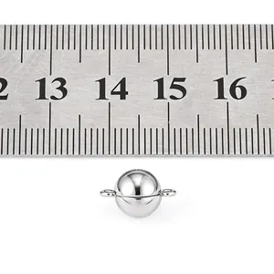 Detailed view of a polished silver magnetic clasp for jewelry measured with a ruler