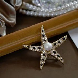 Macro view of vintage golden starfish brooch with central pearl and black crystal detailing