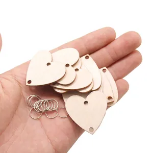 Handheld view of DIY double-hole wooden heart tags with metal rings for crafts