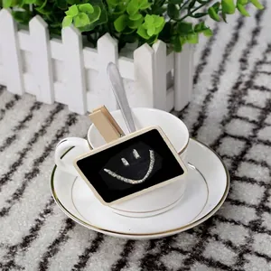 Close-up detail of a mini wooden blackboard memo clip with a smiley face on a tea cup.