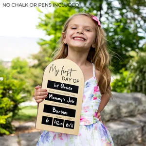 Handcrafted wooden first day of school chalkboard sign held by a child outdoors