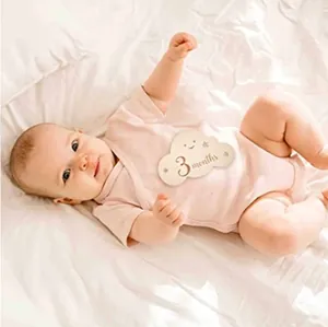 Nahaufnahme einer wolkenförmigen hölzernen monatlichen Meilensteinkarte für Babys als Fotorequisite.