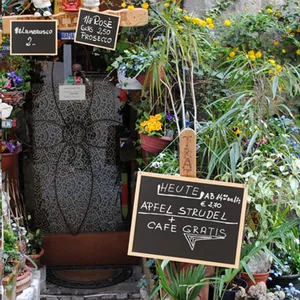 Rustic wooden chalkboard menu display at a cozy cafe entrance decorated with plants