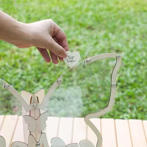 Main déposant un cœur en bois dans un cadre de livre d'or en forme de papillon