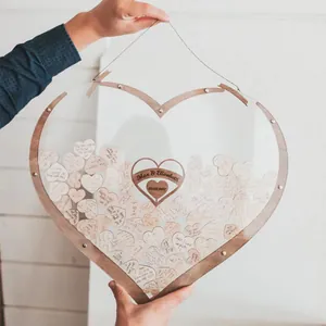 Dettaglio di un libro degli ospiti di nozze a forma di cuore in legno con cuoricini.