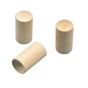 Primo piano di tre diffusori di oli essenziali cilindrici in legno naturale su bianco