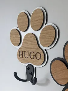 Detalle de un gancho de pared de madera con forma de pata de perro y nombre personalizado