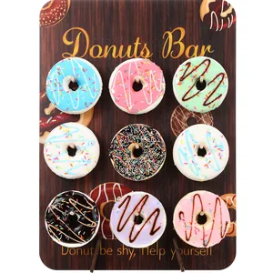 Primer plano de un tablero de madera para donas con nueve donas decoradas