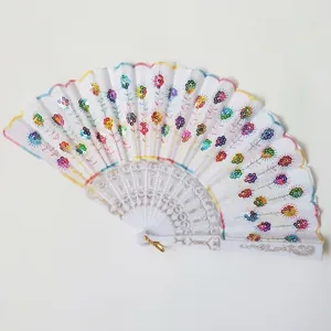 Close-up detail of a white folding fan with colorful sequins and floral embroidery