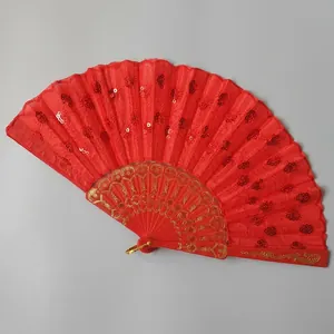 Detailed macro view of a vibrant red sequined folding fan with elegant gold patterns.