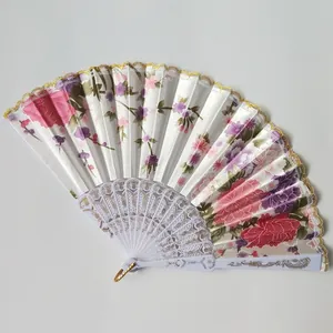Detail view of a white folding fan with floral satin fabric and gold lace trim
