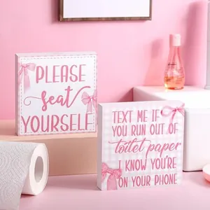 Coppia di divertenti cartelli in legno rosa per bagno con testo e motivi a nastro