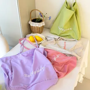 Detailed view of minimalist canvas tote bags in various colors with elegant embroidery