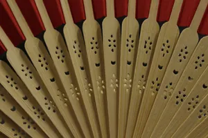 Close-up of bamboo ribs with hollow patterns on a traditional red folding wedding fan