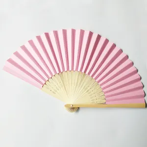 Detailed view of a pink folding paper fan with carved bamboo ribs for wedding DIY